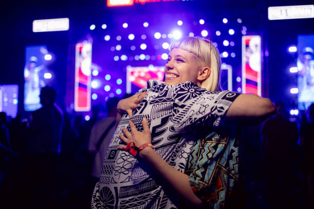 young happy woman embracing her boyfriend during a music festival at night. - concert stock pictures, royalty-free photos & images