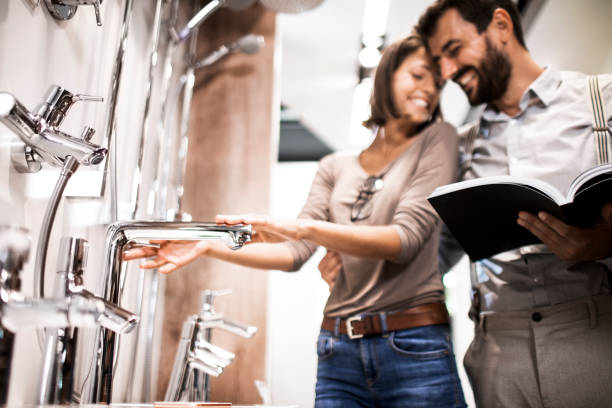 young husband and wife looking for a shower faucet in a specialized bathroom equipment store - home decoration stock pictures, royalty-free photos & images