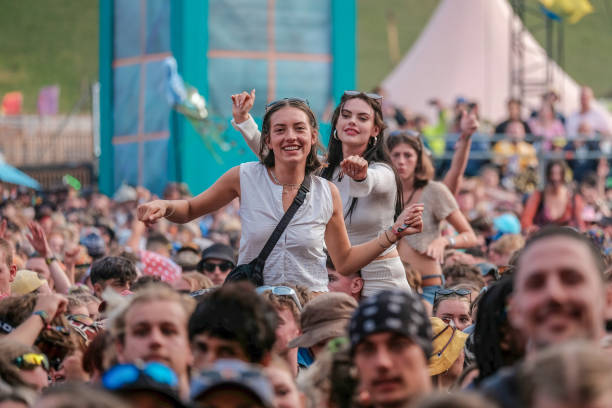 Young lady on the shoulders of a friends in crowd enjoys live music at Boomtown Fair Festival. Boomtown aka Boomtown Fair is a British music festival...