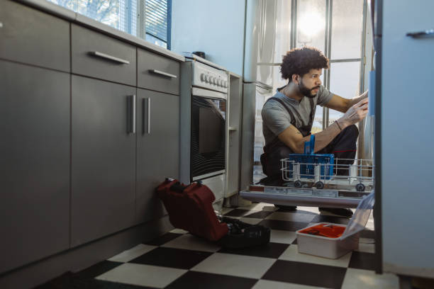 young latin handyman repairs the dishwasher in the client's kitchen - home decoration stock pictures, royalty-free photos & images