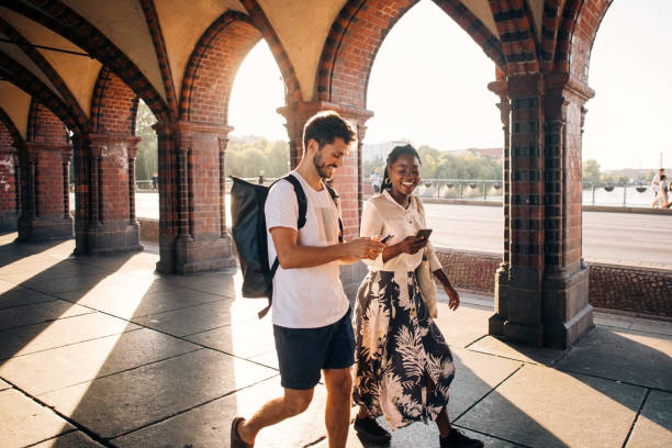 young male and female friends walking on footpath in city - travel stock pictures, royalty-free photos & images