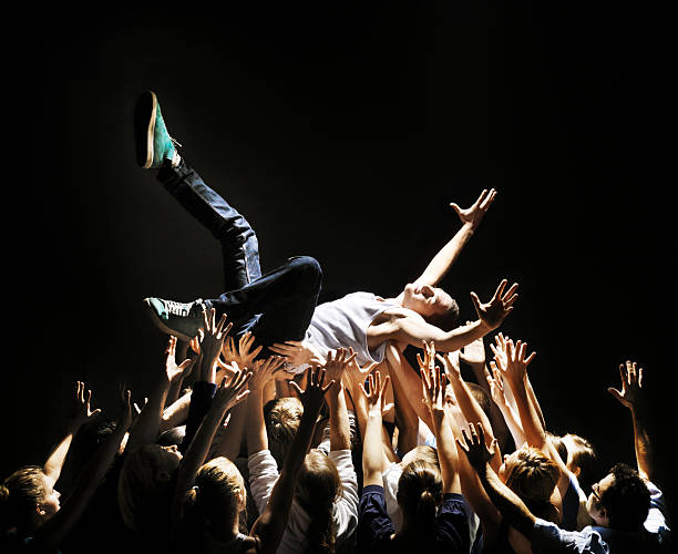 young man beeing carried by group of people - concert stock pictures, royalty-free photos & images