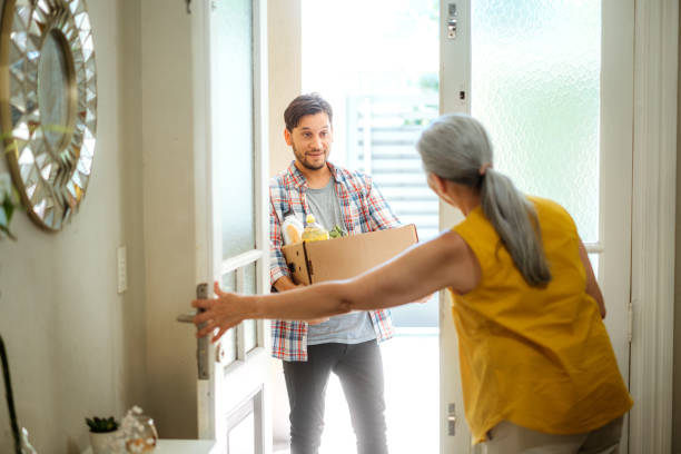 young man delivering groceries to elderly woman at home - food stock pictures, royalty-free photos & images