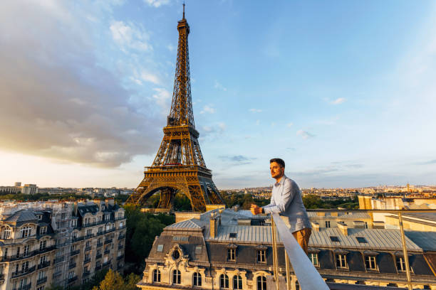young man looking at the sunset from the balcony with eiffel tower in the background, paris, france - travel stock pictures, royalty-free photos & images