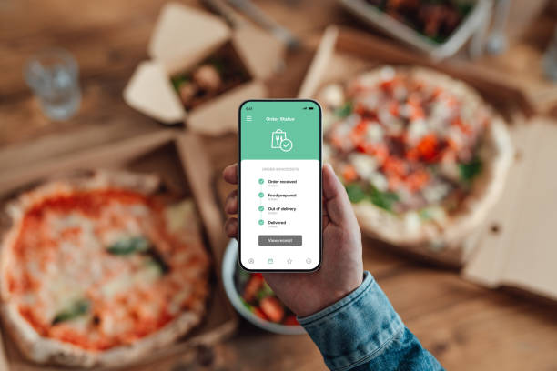 young man ordering food delivery via mobile app on smart phone. - junk food stock pictures, royalty-free photos & images