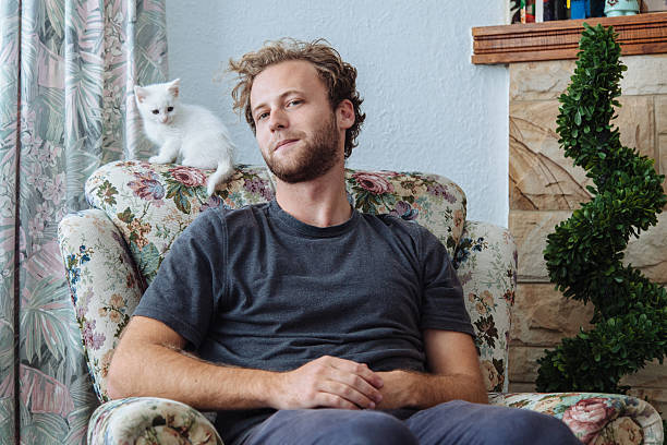 young man sitting at home with small white kitten - home decoration stock pictures, royalty-free photos & images