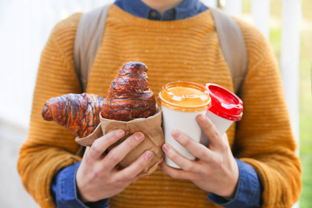 young man with croissant and coffee to go - junk food stock pictures, royalty-free photos & images