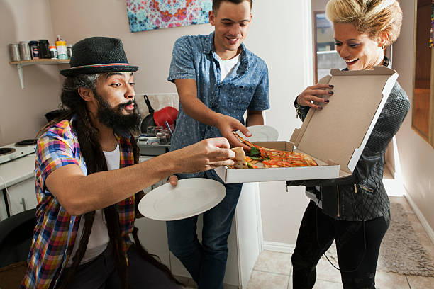 young musicians hanging out and eating takeout pizza - junk food stock pictures, royalty-free photos & images