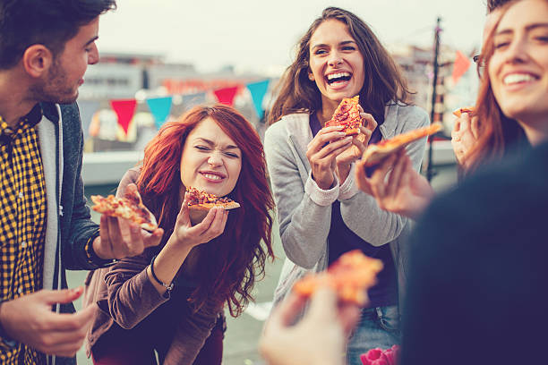 young people eating pizza at party - junk food stock pictures, royalty-free photos & images