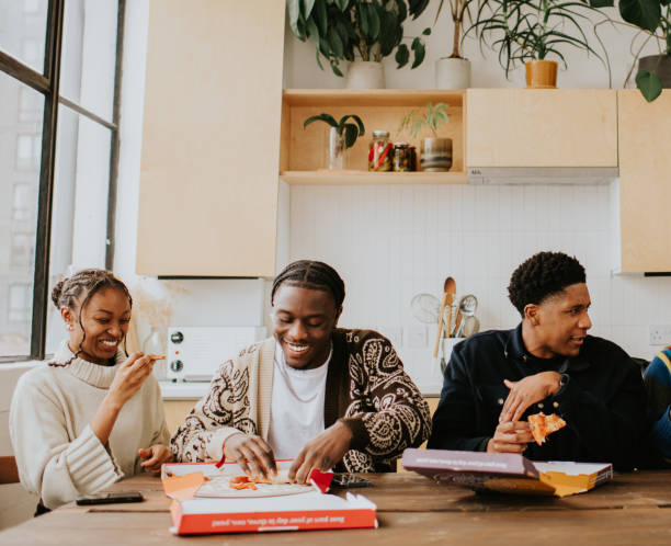 young people enjoy a fresh, delicious pizza, directly from a cardboard pizza box. - junk food stock pictures, royalty-free photos & images