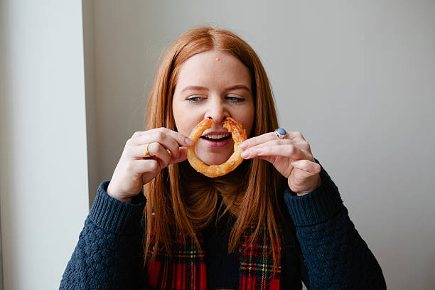 young red haired woman eating junk food - junk food fotografías e imágenes de stock