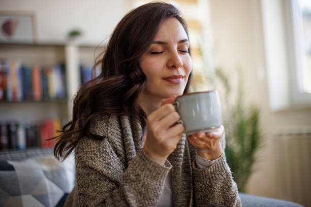 young smiling woman enjoying in smell of fresh coffee at home - coffee stock pictures, royalty-free photos & images