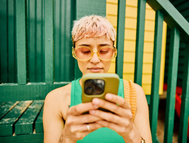 young solo traveller using her phone on vacation - fashion stock pictures, royalty-free photos & images