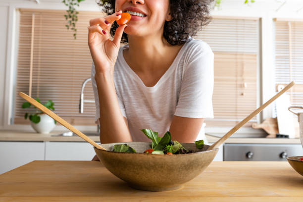 young unrecognisable multiracial african american eating tomato from fresh salad.healthy eating. - food stock pictures, royalty-free photos & images