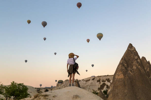 young woman and hot air ballons, goreme, cappadocia, turkey - travel stock pictures, royalty-free photos & images