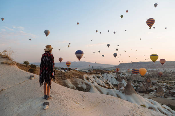 young woman and hot air balloons in the evening, goreme, cappadocia, turkey - travel stock pictures, royalty-free photos & images