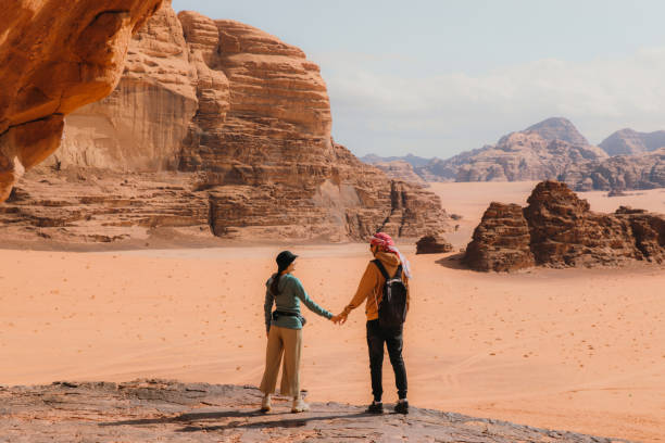 young woman and man traveler contemplating the scenic landscape of wadi rum desert - travel stock pictures, royalty-free photos & images
