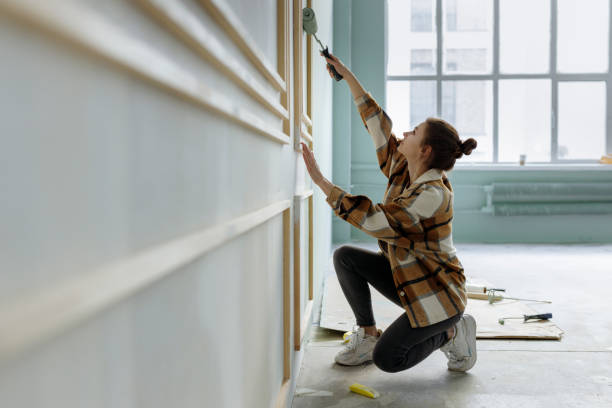 young woman applying paint on wall in apartment - home decoration stock pictures, royalty-free photos & images