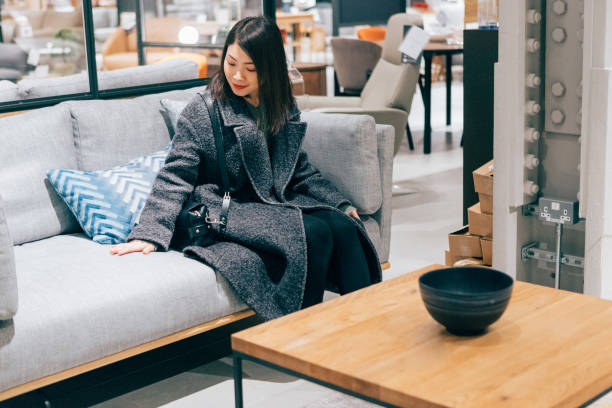 young woman at furniture store choosing sofa - home decoration stock pictures, royalty-free photos & images