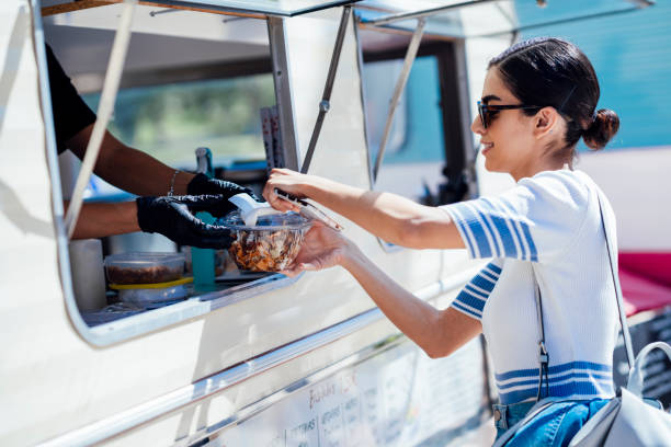 young woman buying take away food from a street food stand - junk food stock pictures, royalty-free photos & images