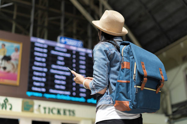 young woman checking her train in timetable board - travel stock pictures, royalty-free photos & images