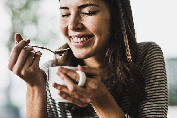 young woman drinking cappuccino, spooning milk froth - coffee stockfoto's en -beelden