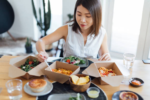 young woman eating delicious takeaway food at home - junk food stock pictures, royalty-free photos & images