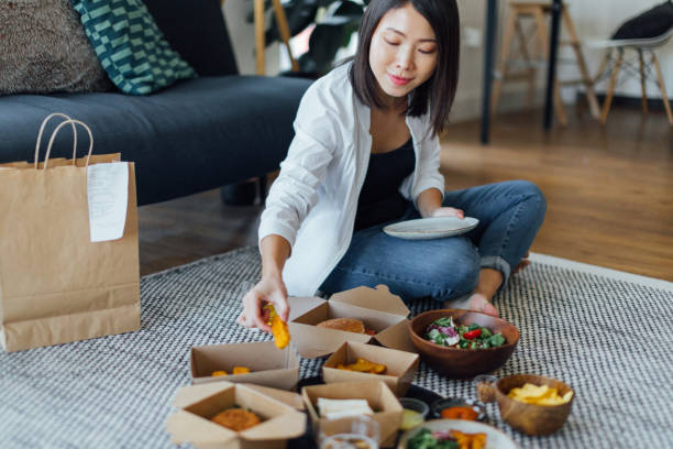 young woman eating fast food at home - junk food stock pictures, royalty-free photos & images