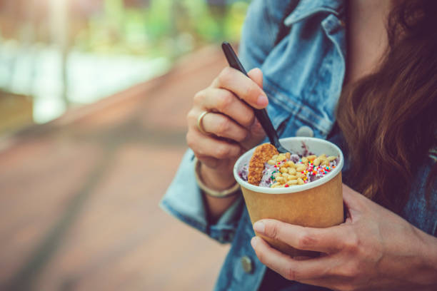 young woman eating healthy rolled ice-cream or yogurt with fruits or berries, cookies, candy and mint - junk food stock pictures, royalty-free photos & images