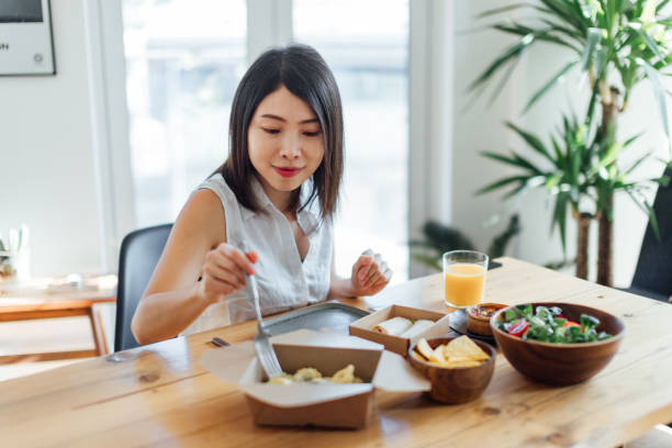 young woman eating healthy takeaway meal at home - junk food stock pictures, royalty-free photos & images