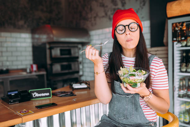 young woman eating salad - food stockfoto's en -beelden
