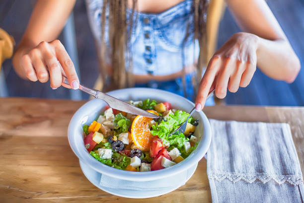 young woman eating salad for lunch - food stock pictures, royalty-free photos & images