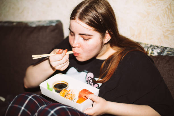 young woman eating sushi at house party - junk food stock pictures, royalty-free photos & images