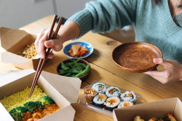 young woman eating takeaway asian meal at home - junk food stock pictures, royalty-free photos & images