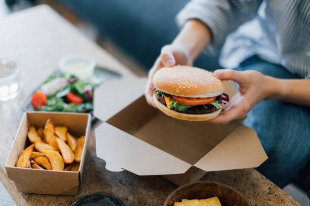 young woman eating takeaway food - junk food stock pictures, royalty-free photos & images