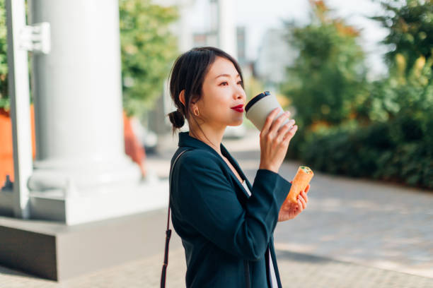 young woman eating wrap sandwich on lunch break outdoors - junk food stock pictures, royalty-free photos & images