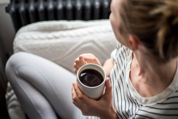 young woman enjoying coffee and relaxing on a sofa - coffee stock pictures, royalty-free photos & images