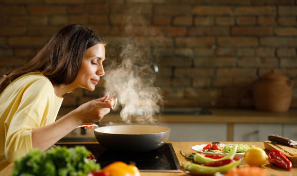 young woman enjoying while cooking meal in the kitchen. - food stock pictures, royalty-free photos & images