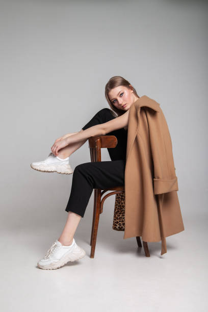 young woman in elegant coat sitting on the chair - fashion stock pictures, royalty-free photos & images