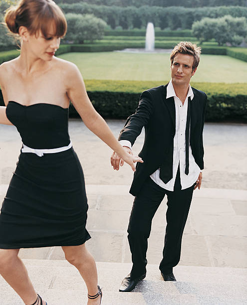 young woman in evening dress leaving young man on steps - garden decoration stock pictures, royalty-free photos & images
