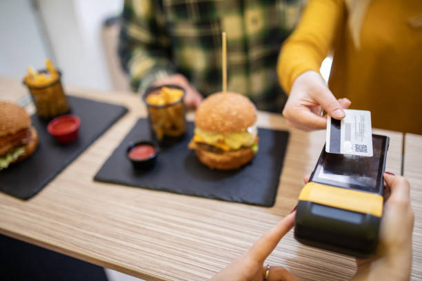young woman making contactless payment for burgers in fast food restaurant - junk food stock pictures, royalty-free photos & images