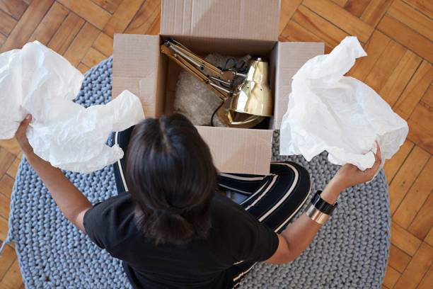 young woman opening box with lamp at home - home decoration stock pictures, royalty-free photos & images