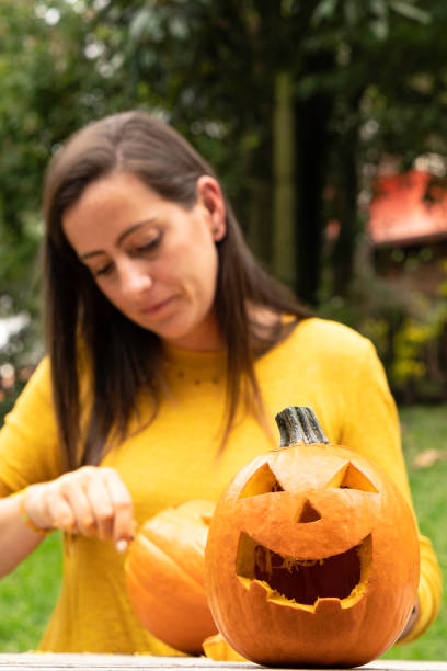 young woman painting and carving halloween pumpkins - garden decoration stock pictures, royalty-free photos & images