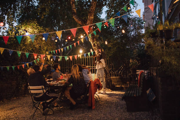 young woman photographing friends during dinner party in backyard - garden decoration stock pictures, royalty-free photos & images
