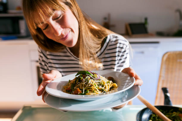 young woman serving vegan pasta dish - food stock pictures, royalty-free photos & images