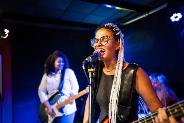 young woman singing and playing bass on a show - concert stock pictures, royalty-free photos & images