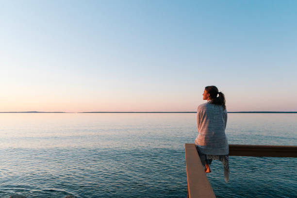 young woman sitting on edge looks out at view - travel stock pictures, royalty-free photos & images