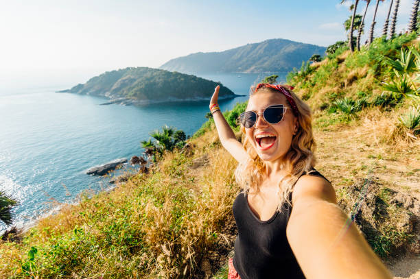 young woman takes selfie, on hillside above sea - travel stock pictures, royalty-free photos & images
