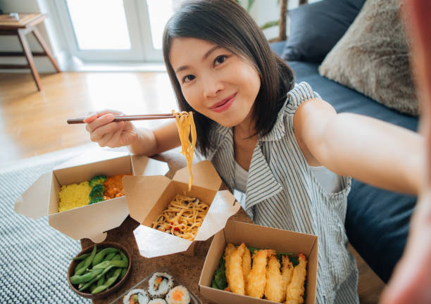 young woman taking selfie while eating takeaway food - junk food stock pictures, royalty-free photos & images