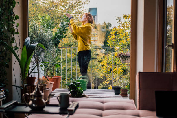 young woman tending to her plants on balcony - garden decoration stock pictures, royalty-free photos & images